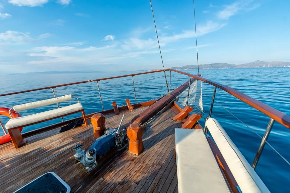 The empty aft deck with varnished wood, cushioned benches and open sea