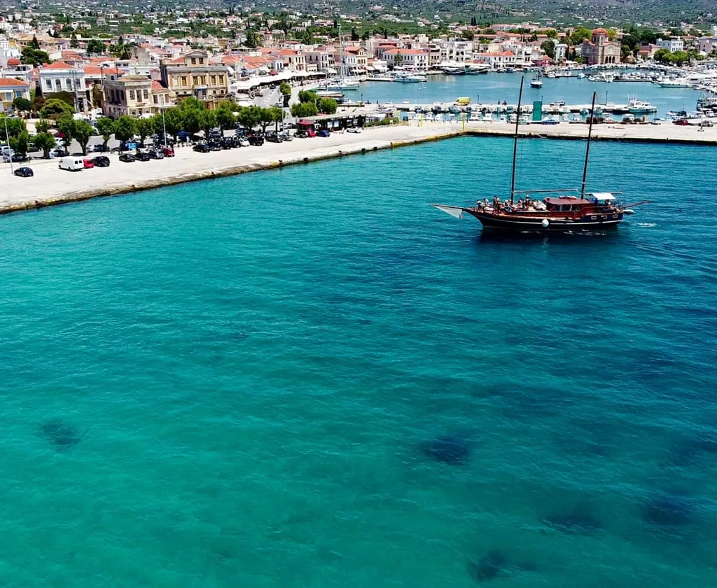 Aerial view of the wooden cruise boat in turquoise water off Aegina harbour