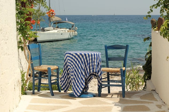 Blue chairs and a small seaside table overlooking the water