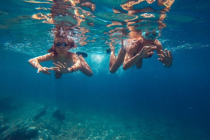 Two snorkellers beneath the surface of clear blue water