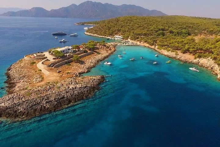 Turquoise water beside a wooded Saronic shoreline